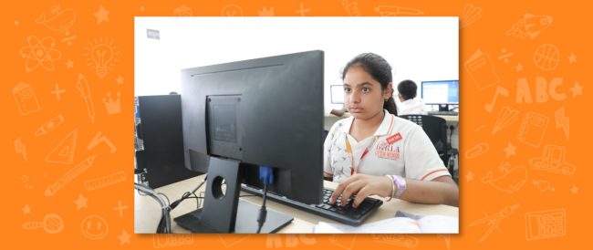 A young student sitting in front of a desktop computer, engaged in learning, highlighting the focus on technology and individual potential at a top CBSE nursery school.